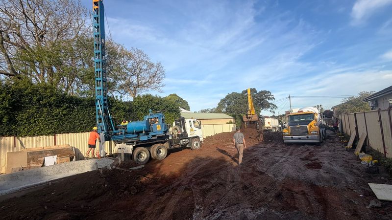 Piling rig and tipper truck on a shored residential excavation site