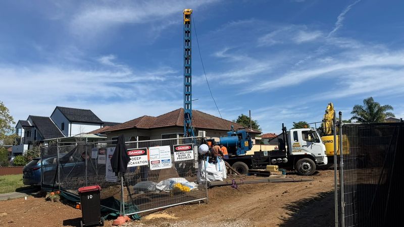 Asbestos removal site with safety signage, piling rig and tipper truck on residential job