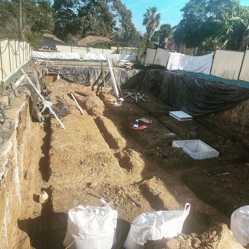 Foundation underpinning excavation showing shored trench, formwork and structural support materials
