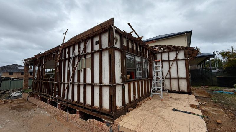 Fibro-clad residential home with external cladding removed before full demolition, asbestos handling